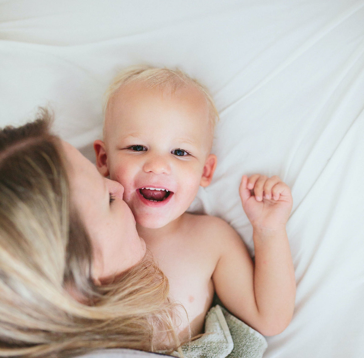 mom leaning over to kiss baby's cheek illustrating comfort during the 2 year old sleep regression