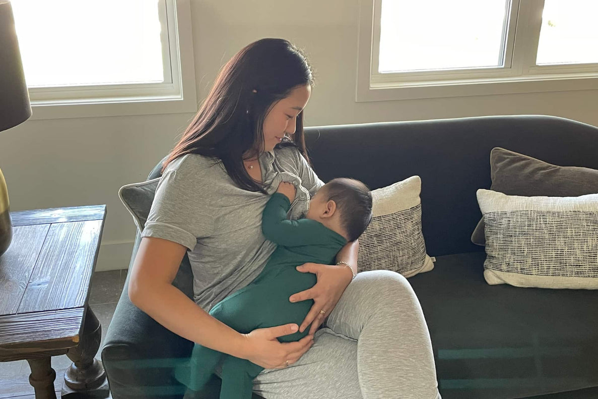 a mom nurses her baby while sitting on a couch