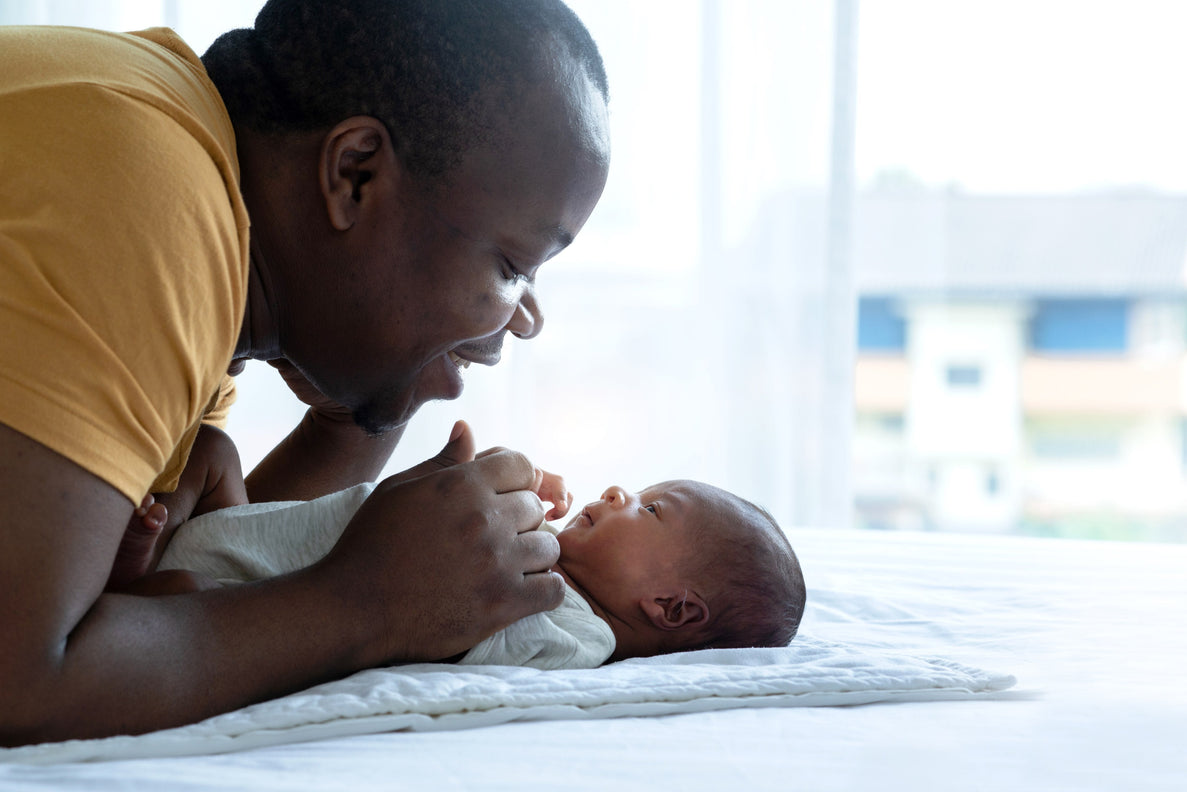 A dad leans over a tiny newborn demonstrating newborn face to face time