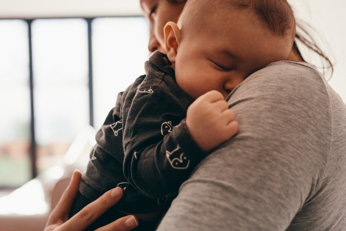 a closeup of a sleeping baby being held over moms shoulder