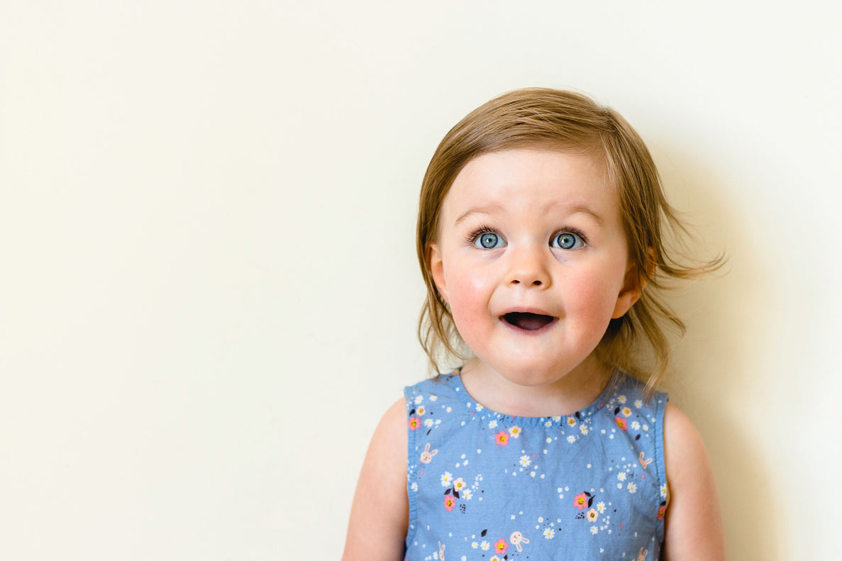 a picture of a joyful young girl wearing a blue dress. She looks surprised