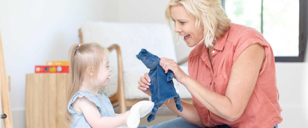 A woman and a girl with blonde hair play with loveys together