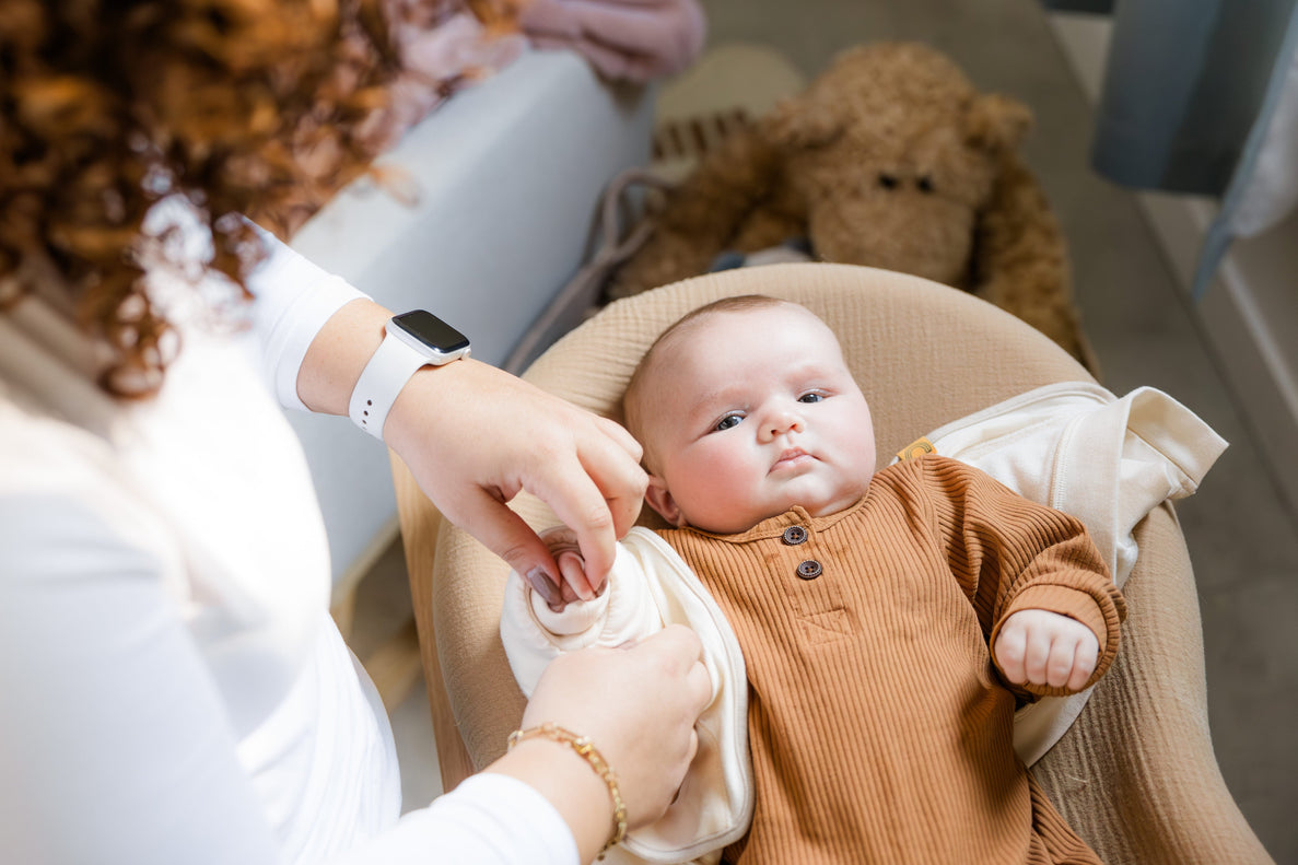 mom putting baby's arm in Jacky, the swaddle transition jacket