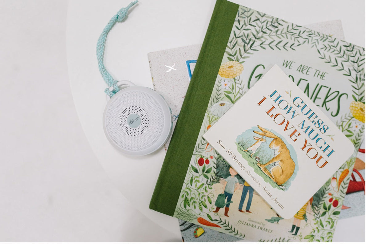 a portable sound machine lays on a white table next to a stack of baby and children's books