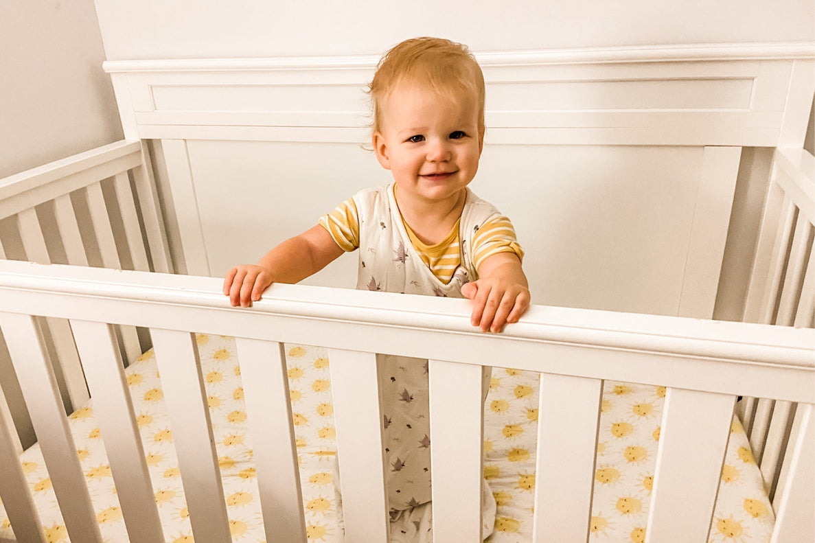 a baby standing in their crib looks like they just woke up