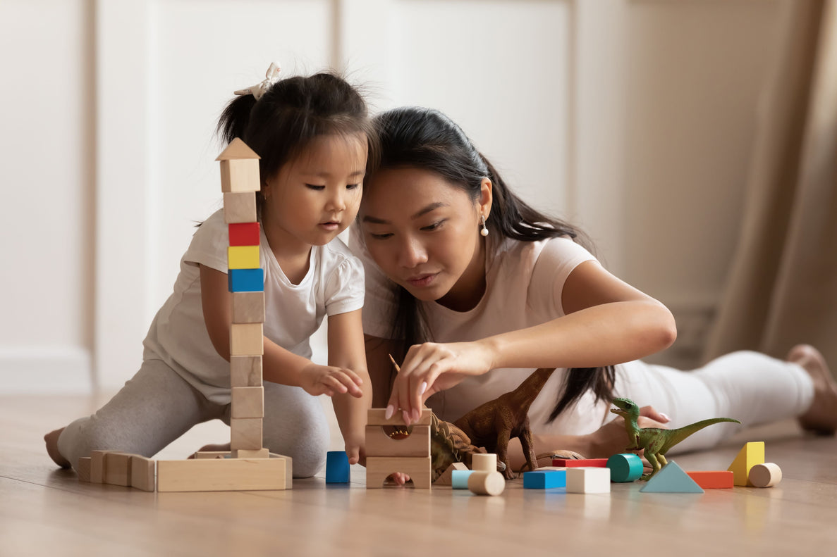 a toddler and her mom play with building blocks on the floor