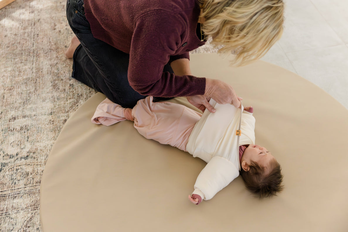 Jacky, the swaddle transition jacket being put on a baby