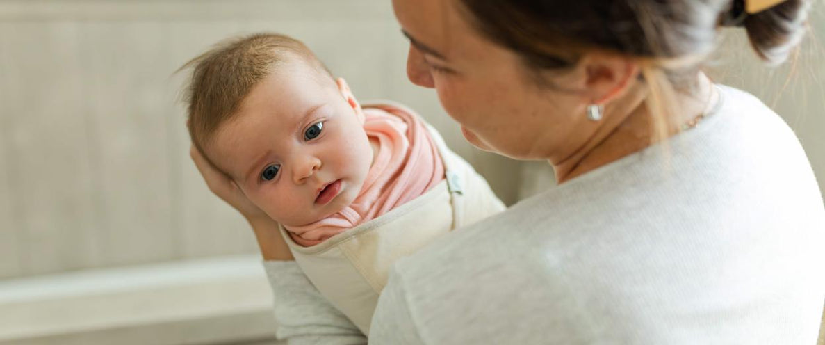 Mom cradles her swaddled newborn and looks at her lovingly
